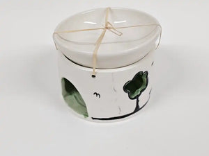 A white ceramic dog toy or chew holder with a matching lid, decorated with a green clover and black line art, tied with a string.