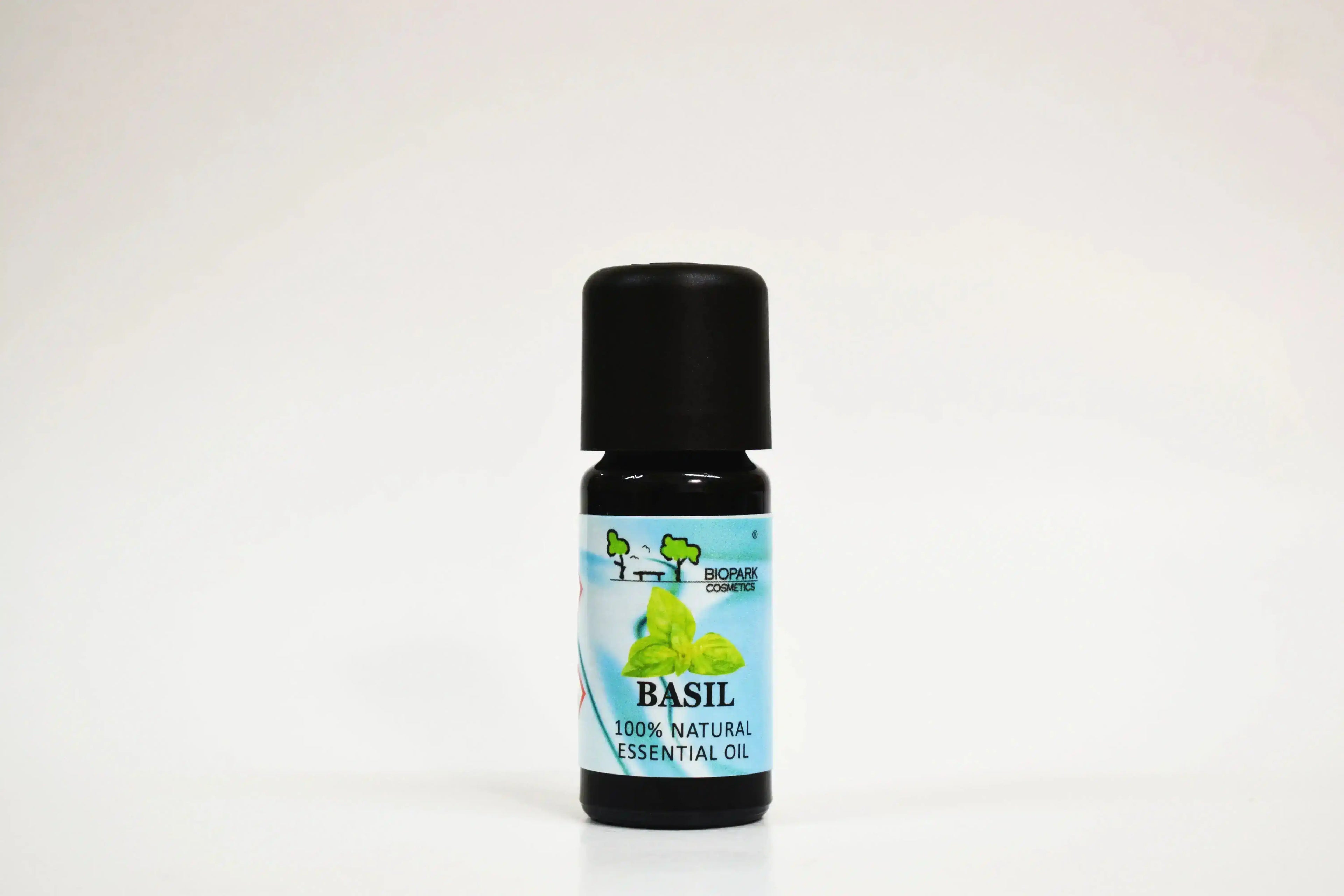 Bote de aceite esencial de albahaca sobre fondo blanco