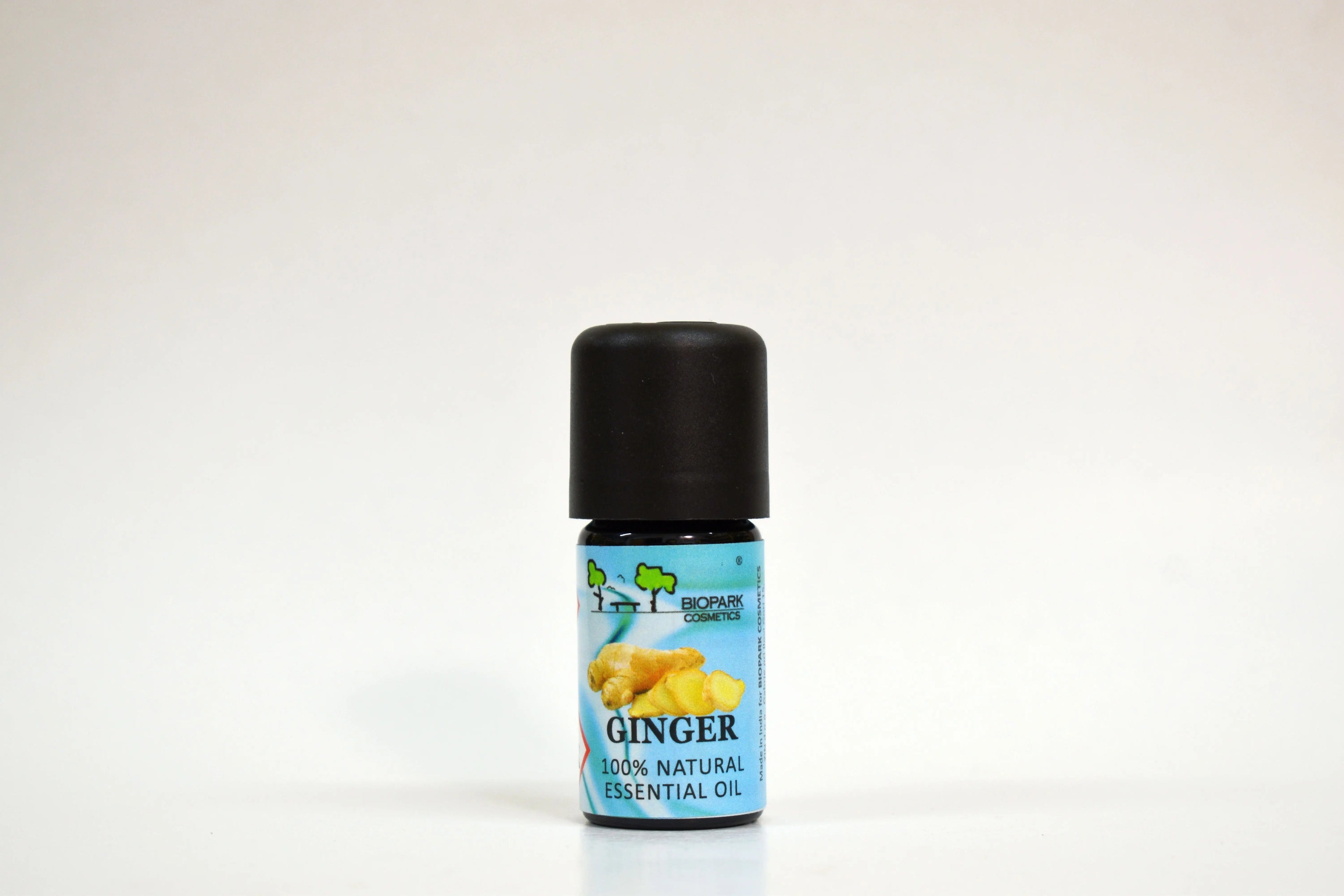 Bottle of ginger essential oil with a black cap on a white background
