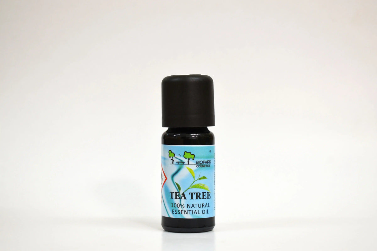 Botella de aceite esencial de árbol de té con una etiqueta azul sobre fondo blanco