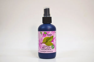 Botella de hidrosol de hoja de laurel ecológico con una etiqueta rosa sobre fondo blanco