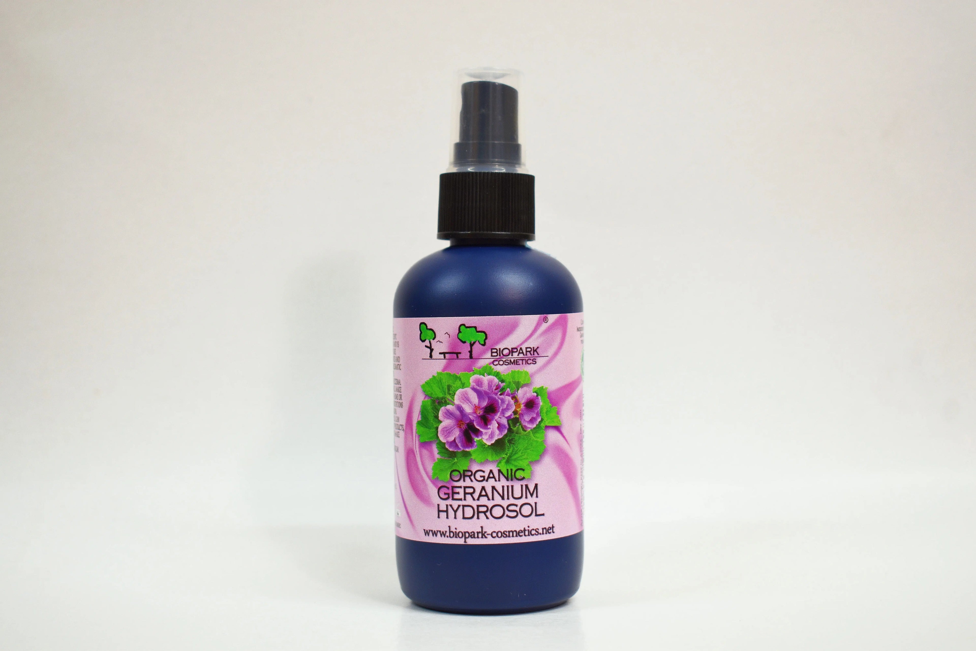 Bottle of organic geranium hydrosol with a pink label on a white background