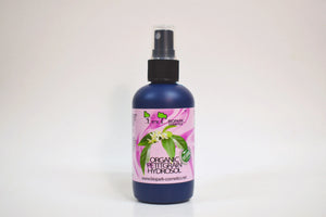 Bottle of organic facial toner with a pink label on a white background