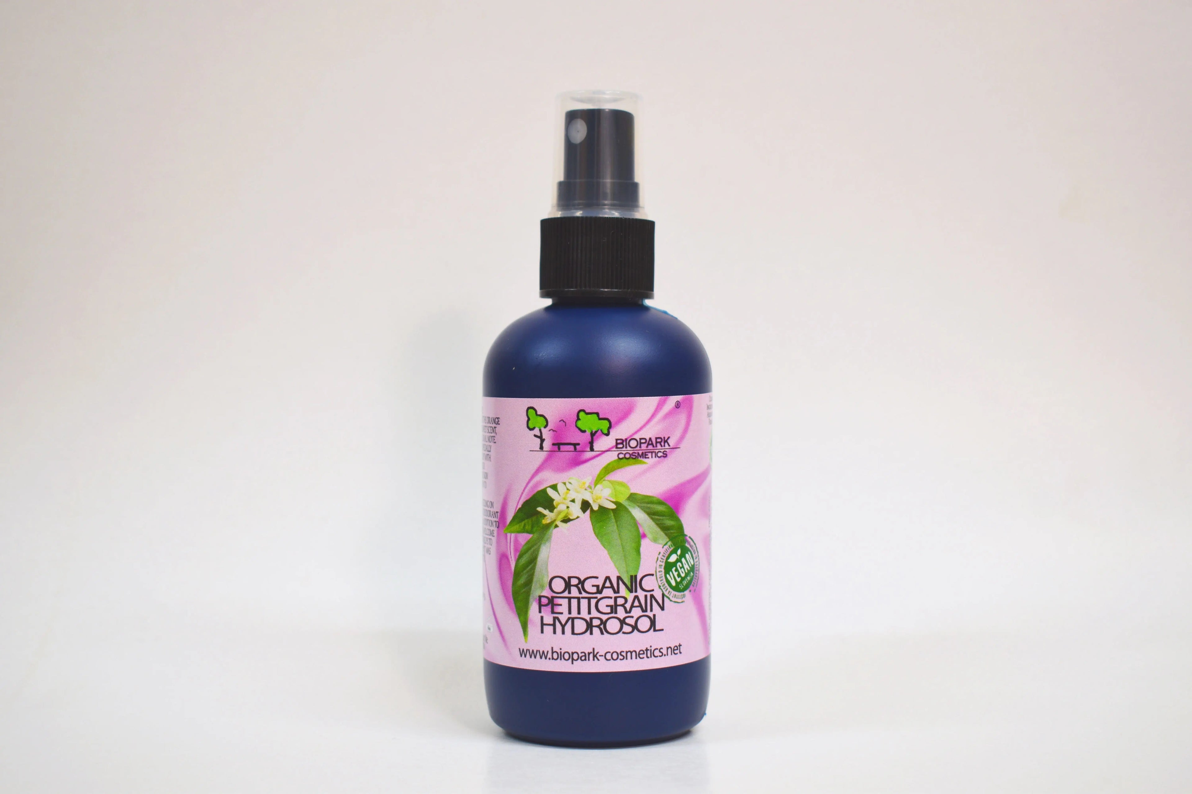 Bottle of organic facial toner with a pink label on a white background