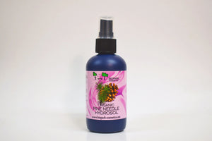 Bottle of organic pine needle hydrosol with a pink label on a white background