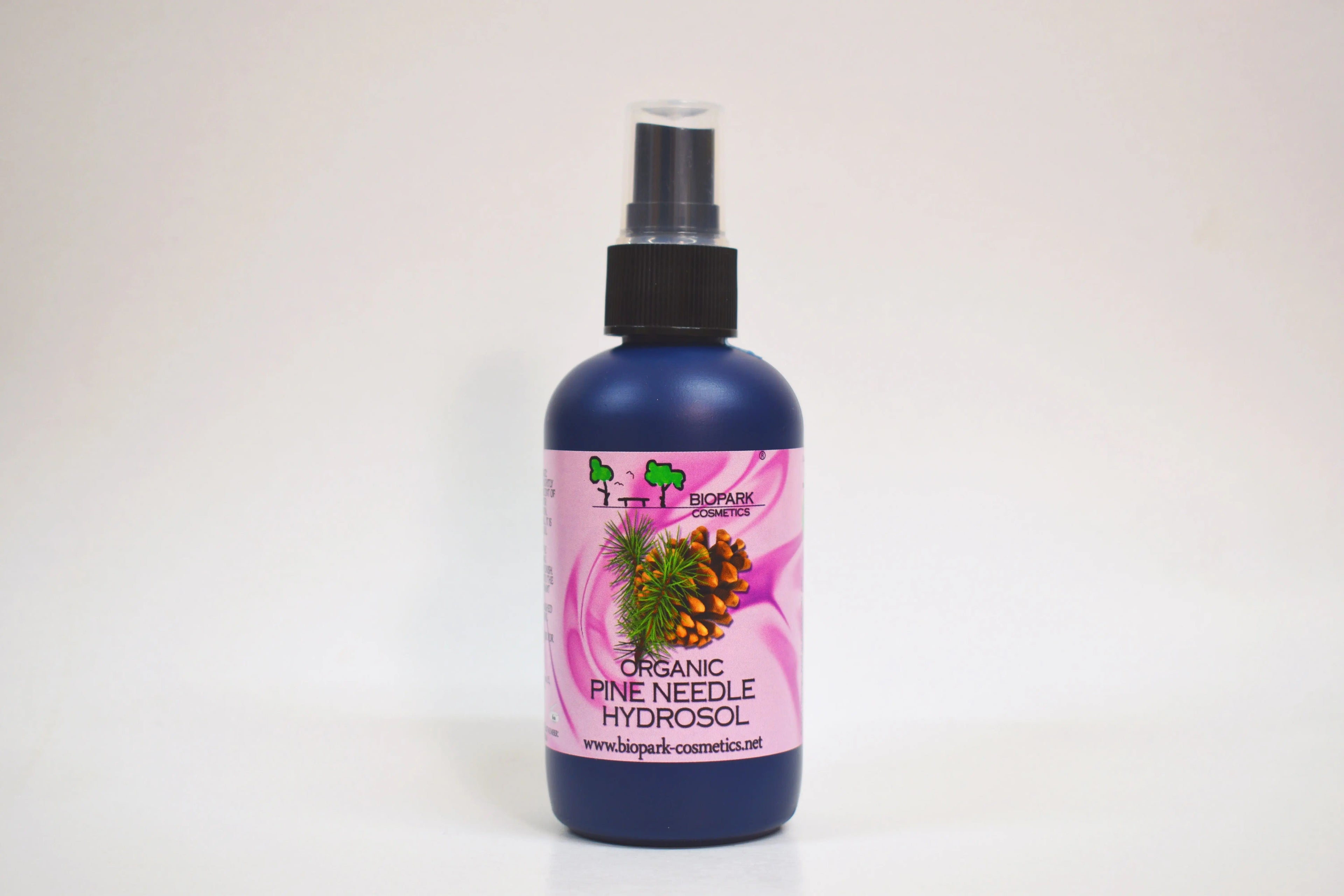 Bottle of organic pine needle hydrosol with a pink label on a white background