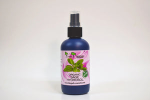 Bottle of organic sage hydrosol with a pink label on a white background