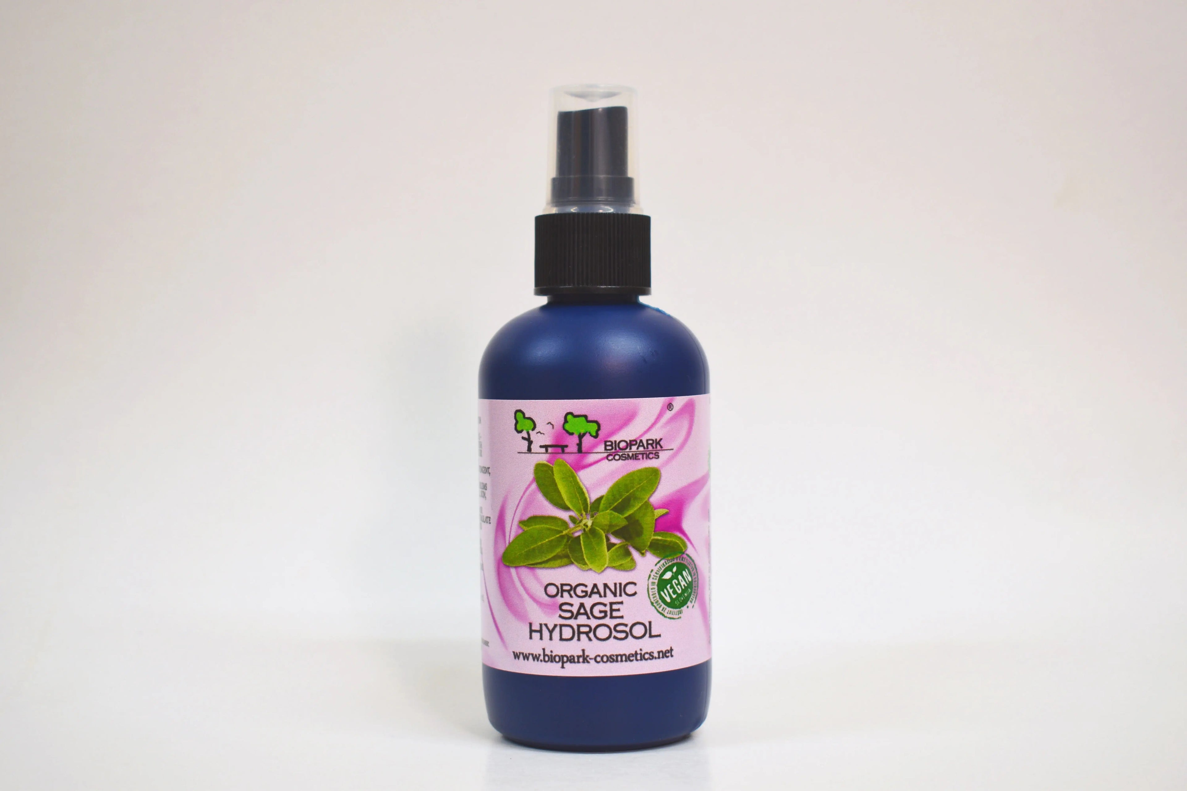 Bottle of organic sage hydrosol with a pink label on a white background