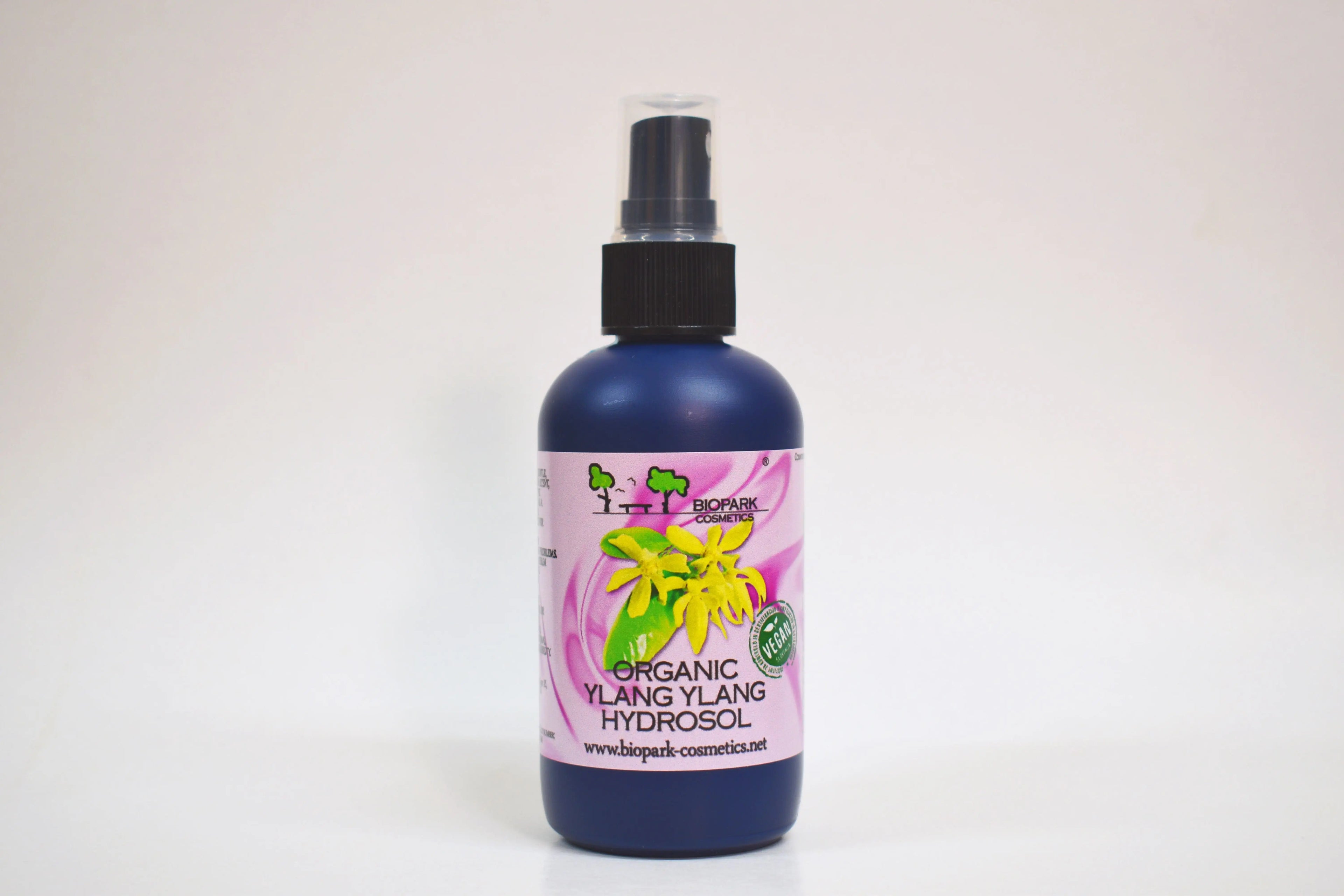 Bottle of organic ylang ylang hydrosol with a pink label on a white background