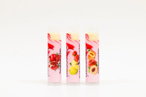 Three lip balm tubes with fruit illustrations on a white background