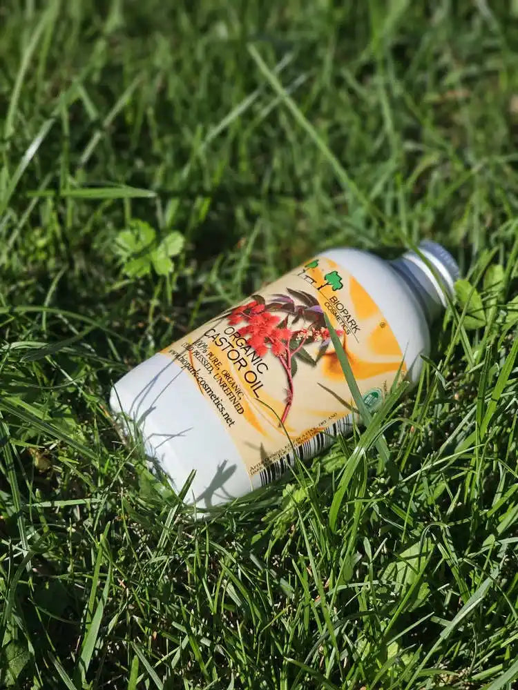 A bottle of Organic Herbal Hair Growth Serum lying on green grass outdoors.