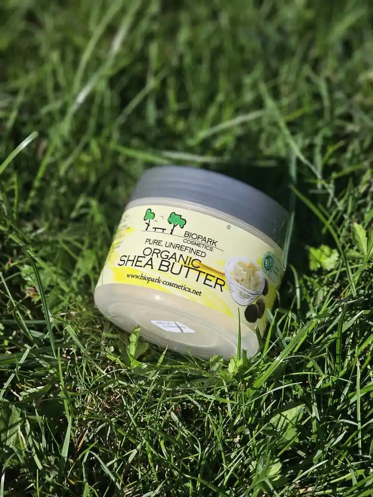 A jar of BioPark Organics Organic Shea Butter resting on a bed of green grass.