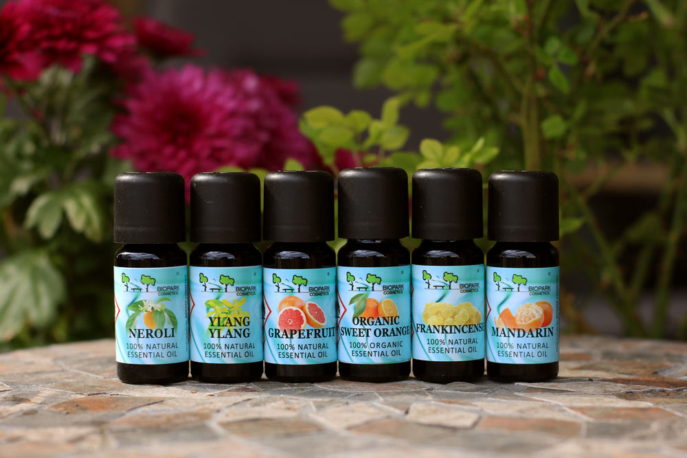 Set of essential oil bottles with labels in front of flowers