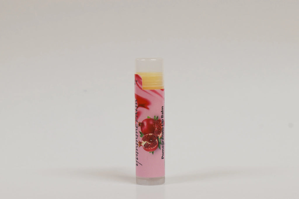 Lip balm with a pink label featuring pomegranate graphics on a white background
