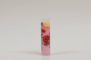 Lip balm with a pink label featuring pomegranate graphics on a white background